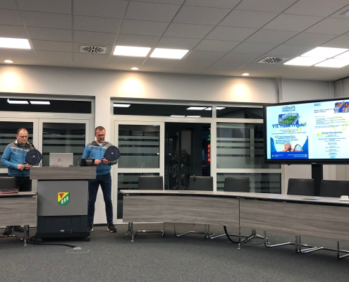 Zwei Personen mit Padel-Tennisschlägern in der Hand präsentieren ihr Projekt auf einer Sitzung